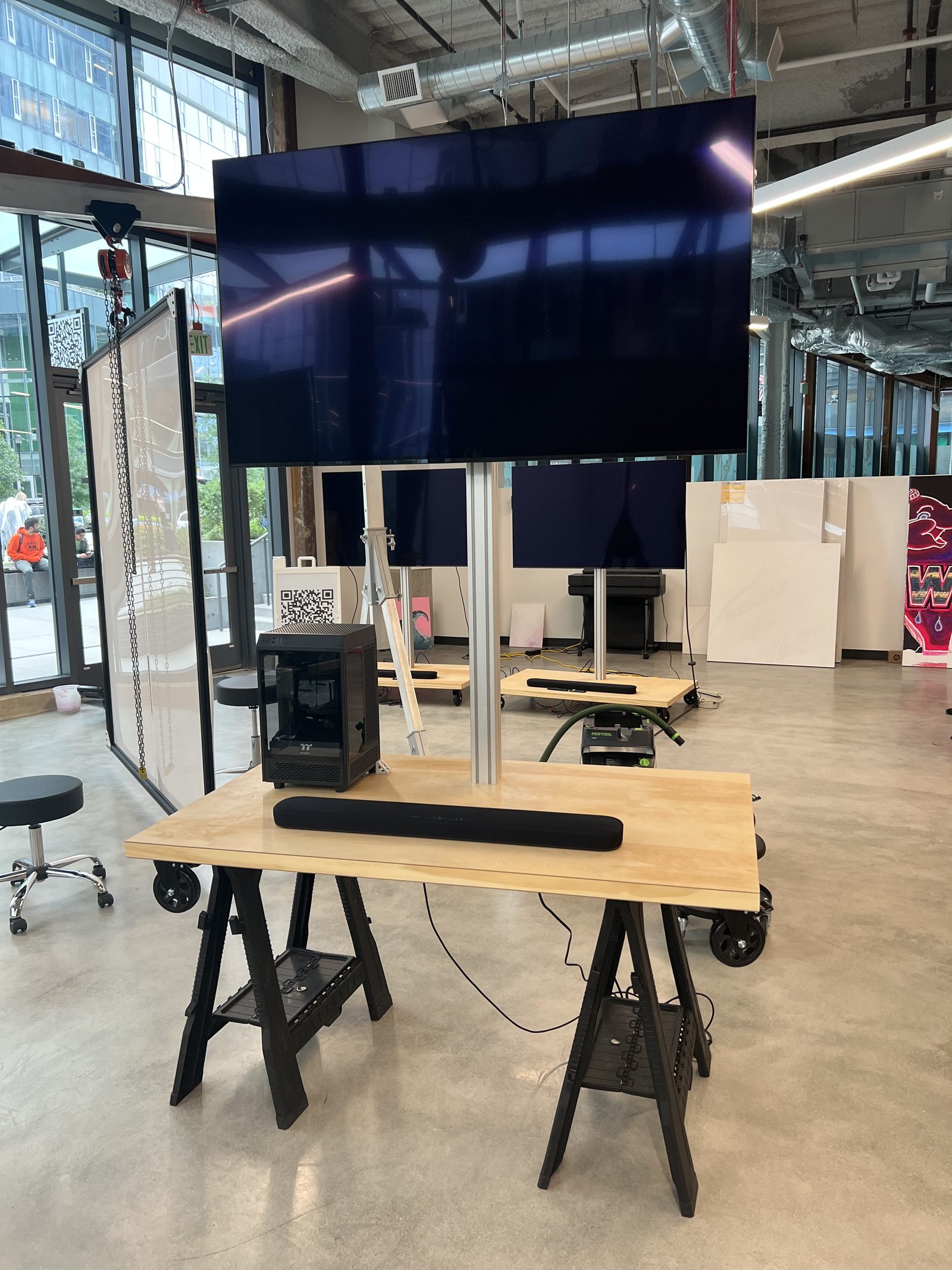 A completed station on the workshop sawhorses before install — TV mounted, PC and soundbar fitted, screen dark