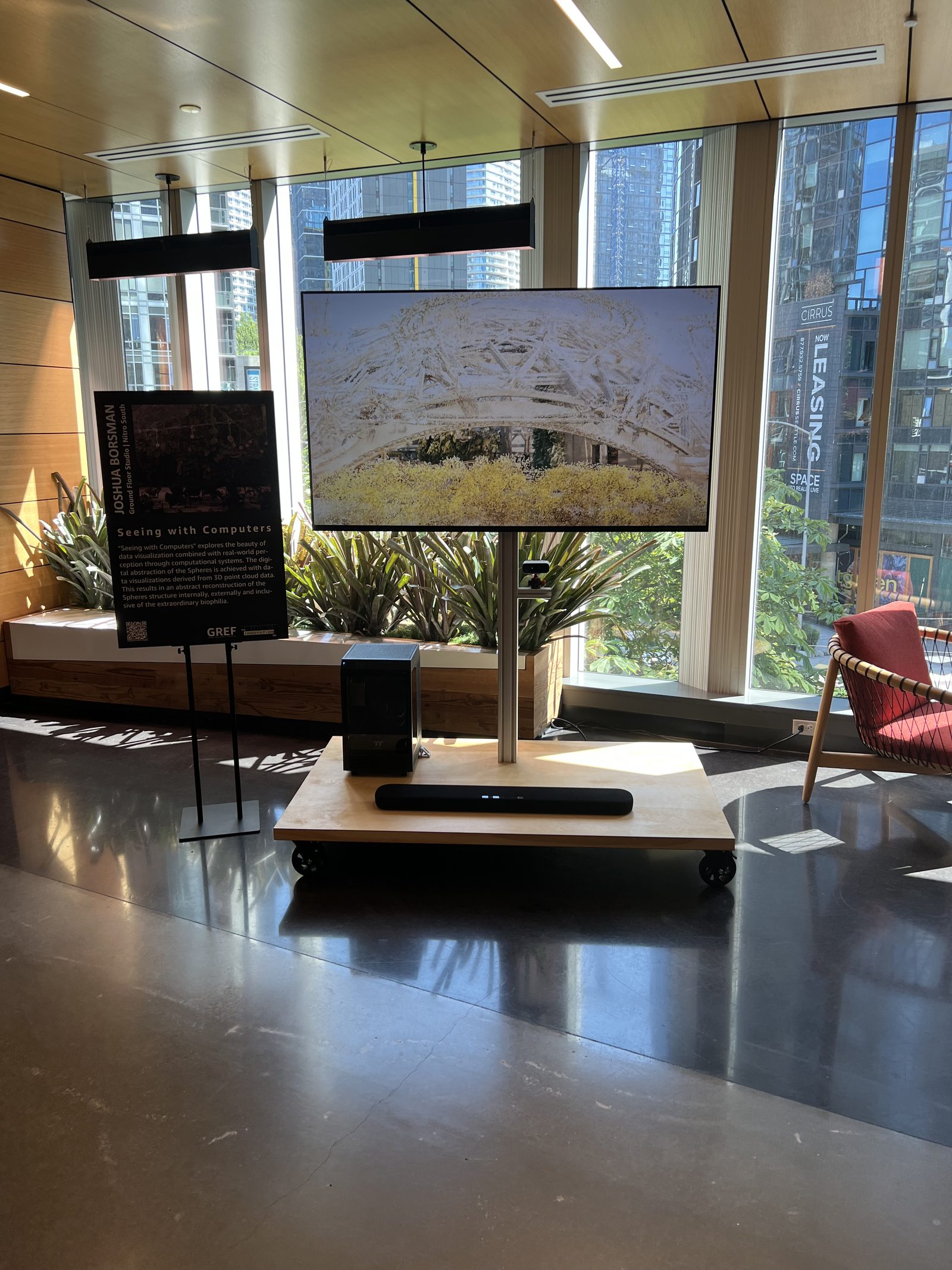 The exhibit installed in an office lobby with planters and seating visible